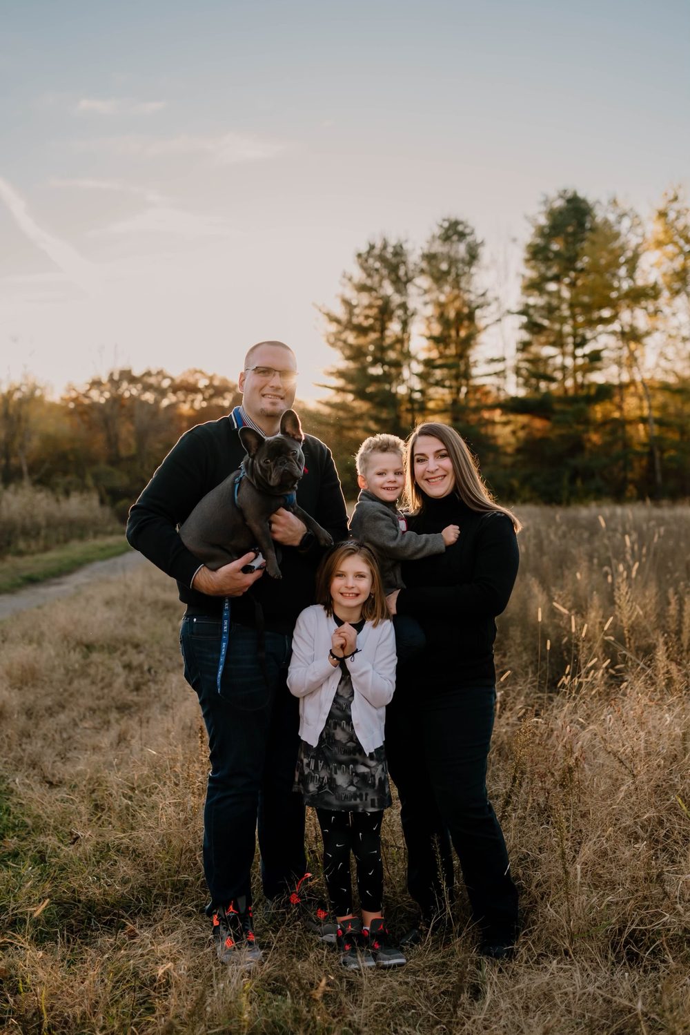 Matt Chapman with his wife, their two children, and their dog in a field at sunset