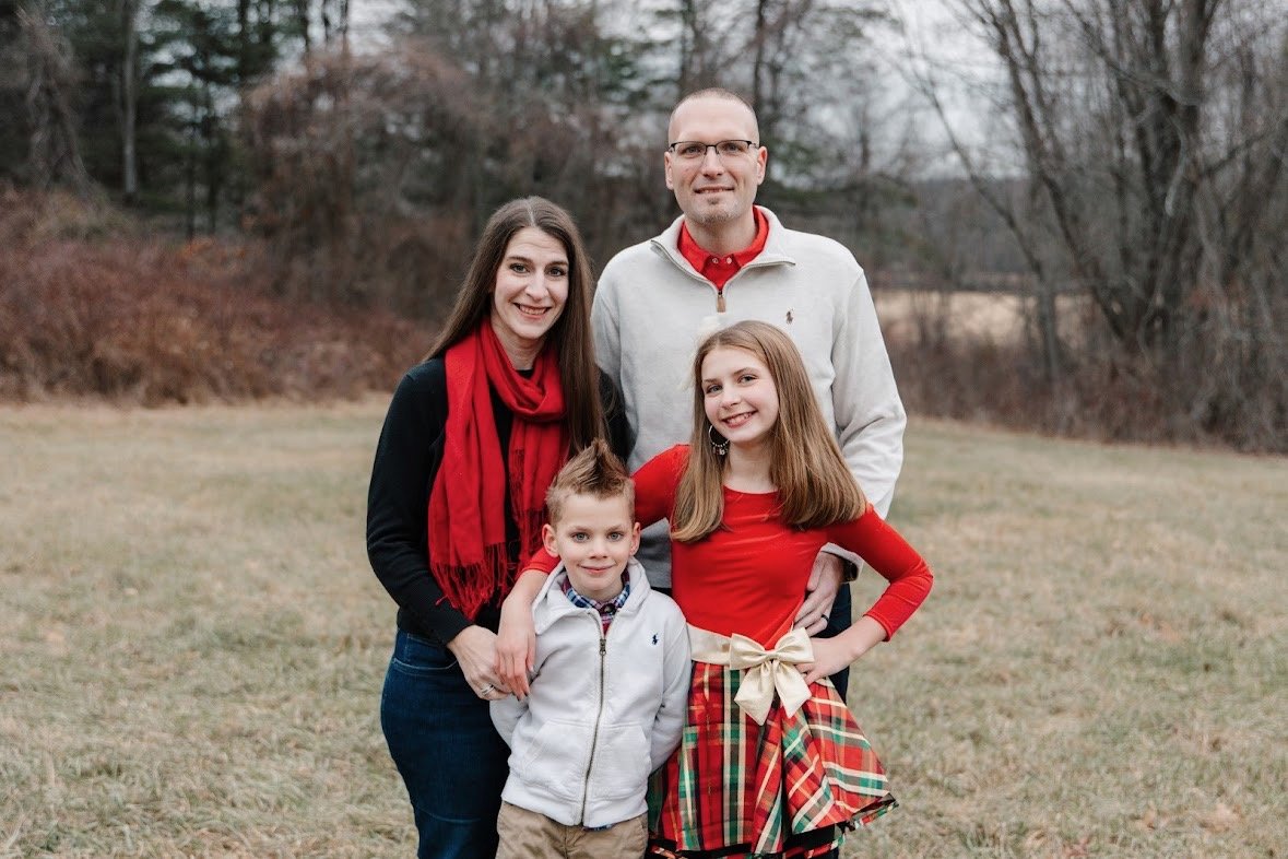 Matt Chapman with his wife and their two children, smiling together in a field